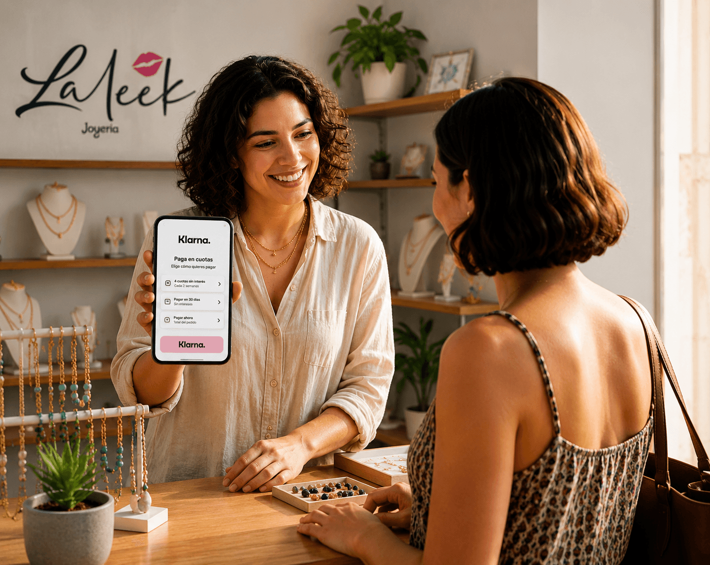 Dependienta de joyería muestra opciones de pago con Klarna en un smartphone a una clienta.